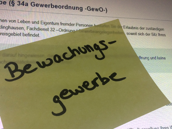 Gelber Klebezettel auf dem handschriftlich das Wort Bewachungsgewerbe geschrieben steht  